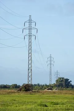 High voltage power lines and steel lattice transmission towers standing in .. Stock Photos