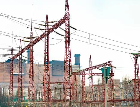 High-voltage power lines on the background of an industrial plant. Stock Photos