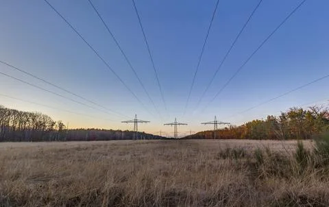 High voltage power lines over a field at sunset 写真素材