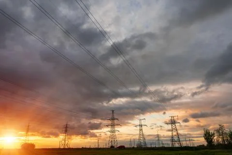 High-voltage power lines passing through a green field of wheat, on the backg Stockfoto's