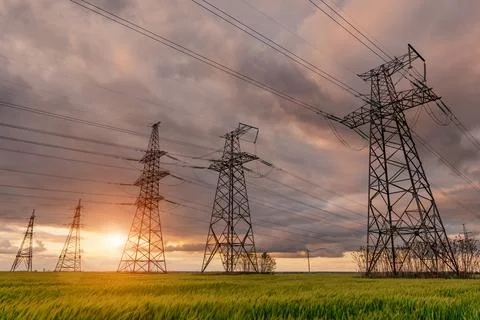 High-voltage power lines passing through a green field, on the background of  Stockfoto's