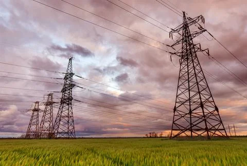 High-voltage power lines passing through a green field, on the background of  Stock Photos