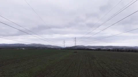 High-voltage power lines stretching across a field under a cloudy autumn sk.. Vídeo Stock 297178035