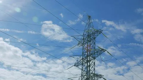 High Voltage Power Lines Stretching Beneath a Clear Blue Sky on a Bright Sunny D 写真素材