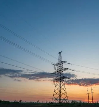 High-voltage power lines at sunset or sunrise. High voltage electric transmis Stock Photos