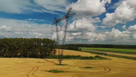High voltage power lines tower standing in a wheat field 스톡 동영상 307107692