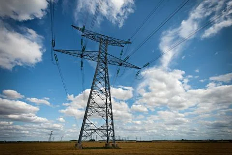 High voltage pylons on blue cloudy sky background Stock Photos