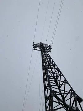 High-voltage tower against the background of the sky in a snowfall. Stock Photos