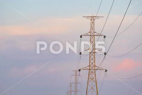 High voltage tower and line cables, in sunset sky background Stock Photos