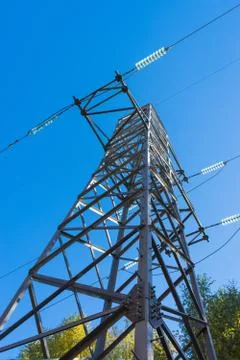 High voltage tower, power lines on blue sky background. Bottom view Stock Photos