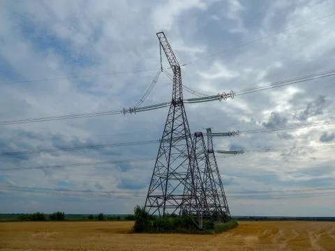 High voltage tower standing in a field with wires Stock Photos