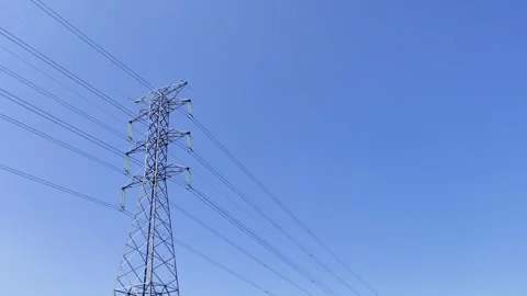 High-voltage tower stands tall against vivid blue sky Stock Footage 338247297