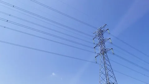 High-voltage tower stands tall against vivid blue sky 스톡 동영상 338247299