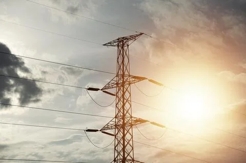 High voltage towers at sunset background. Power lines against the sky Stock Photos