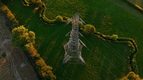 High voltage transmission tower above agricultural landscape at golden hour Видео 338389238