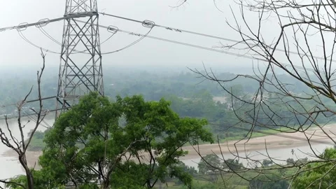High-voltage transmission tower overlooking a river and forest landscape Vídeos de archivo 337926464