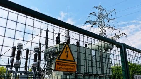 High Voltage Warning Sign with Electricity Pylon and Transformer Stock Photos