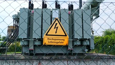 High Voltage Warning Sign in Front of Large Electrical Transformer Stock Photos