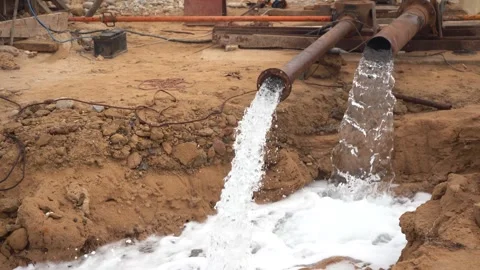 High-Volume Groundwater Pumping from Rusty Metal Pipes into Dirt Trench sound Vídeos de archivo 334181434
