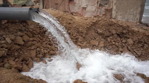 High-Volume Water Discharging from Plastic Pipe Near Housing Settlement Stock Footage 334182575