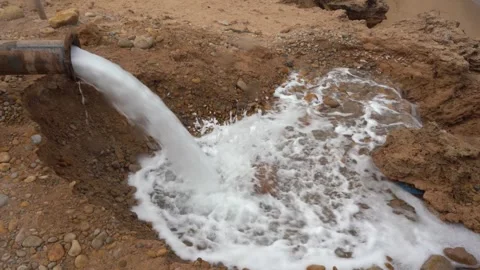 High-Volume Water Pumping from Rusty Industrial Pipe into Rocky Dirt Basin Vídeos de archivo 334181825