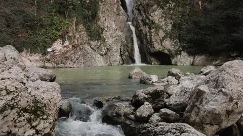 A high waterfall falls from a cliff into a clear lake. Sochi, Russia. Stock Footage 144821708
