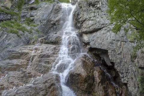 High waterfall on a small river among rocks and green trees Stock Photos