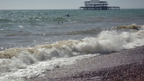 High waves at Brighton pebbled coast, burned pier at far, 4k 스톡 동영상 116128983