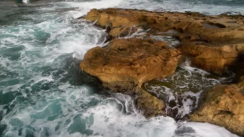 High waves of the ocean break on a rocky beach. Shooting from a drone. Stock Footage 233595555
