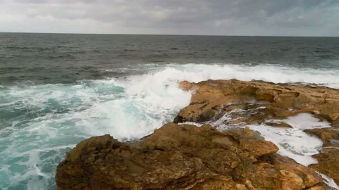 High waves of the ocean break on a rocky beach. Shooting from a drone. Stock Footage 233595643