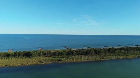 High wide drone panorama tracking the long sand spit strip separating the green Stock Footage 336553643