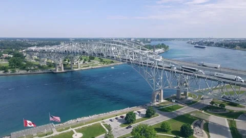 High Wide Drone View of Blue Water Bridge with US and Canadian Flags Stock Footage 312010899