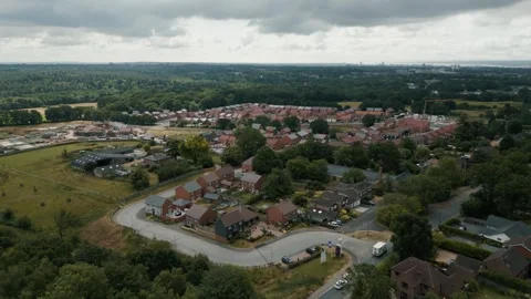 High wide move over a local village of red brick houses green belt Stock Footage 296822948