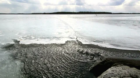 High wind moving water between ice and a rocky shore Stock Footage 36459482