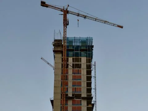 Highrise building under construction with tower crane, scaffolded upper flo.. Stock Photos