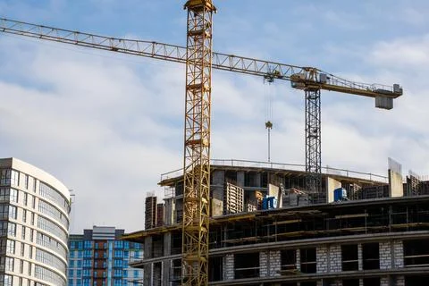 Highrise development with crane lifting precast elements amidst urban Stock Photos