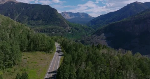 Highway 145 cutting through dense evergreen forest in the San Juan Mountains Stock Footage 328575029