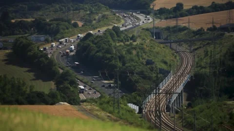 Highway and railway running parallel in rural landscape, cars and train in Stock Footage 268773725