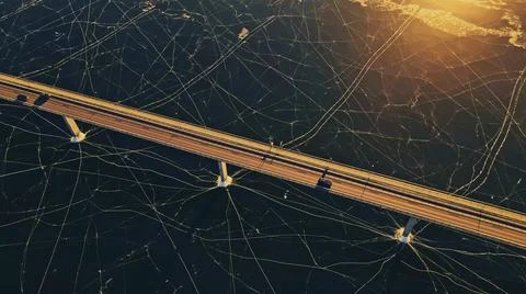 Highway bridge spanning a large body of frozen water covered in thick ice. Stock Photos