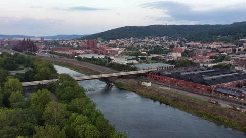 Highway bridge spans wide Lehigh River beside red brick warehouses and railroad Stock Footage 340970626