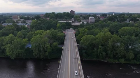 Highway bridge spans wide river lined with dense green tree canopy, cars cross Stock Footage 340970491
