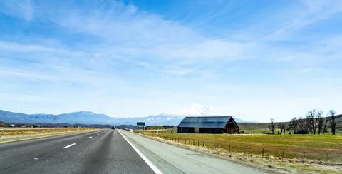 Highway with a building and fields on the roadside Fotos de archivo