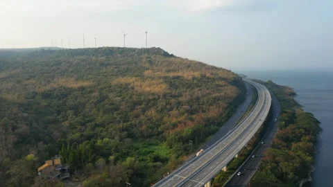 Highway curving through forested hills with wind turbines Stock Footage 288982092
