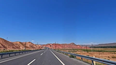Highway drive through red mountains in wide road-level view Stock Footage 343805298