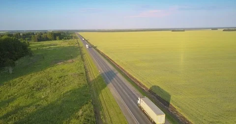 Highway with driving trucks lorries between field and groves Stock Footage 98552721