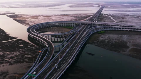 Highway interchange curving over coastal bay and tidal flats in early morning Видео 348782852