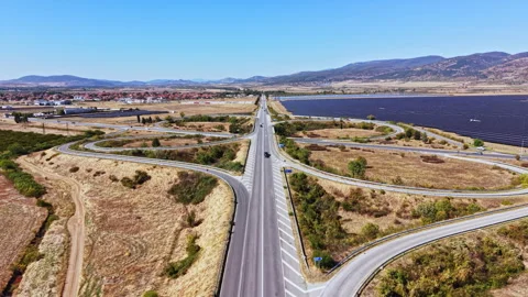 Highway intersection near a town with fields, solar panels, and a water canal Stock Footage 347751576