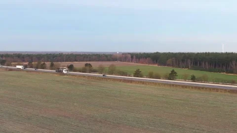 Highway next to a forest with windmill in background Stock Footage 240388194