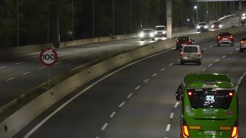 Highway night traffic with 100 speed limit sign and green bus Stock-Footage 334492061