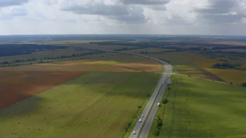 Highway road between colored fields with grass and sheaves of hay. Video stock 194516631